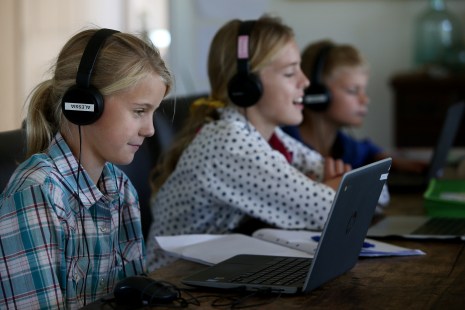Des enfants utilisent leur appareil électronique pour faire l'école à la maison.