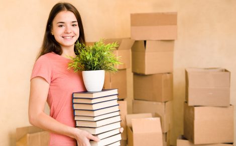 Jeune femme déménagement au collège, tenant des livres et des plantes