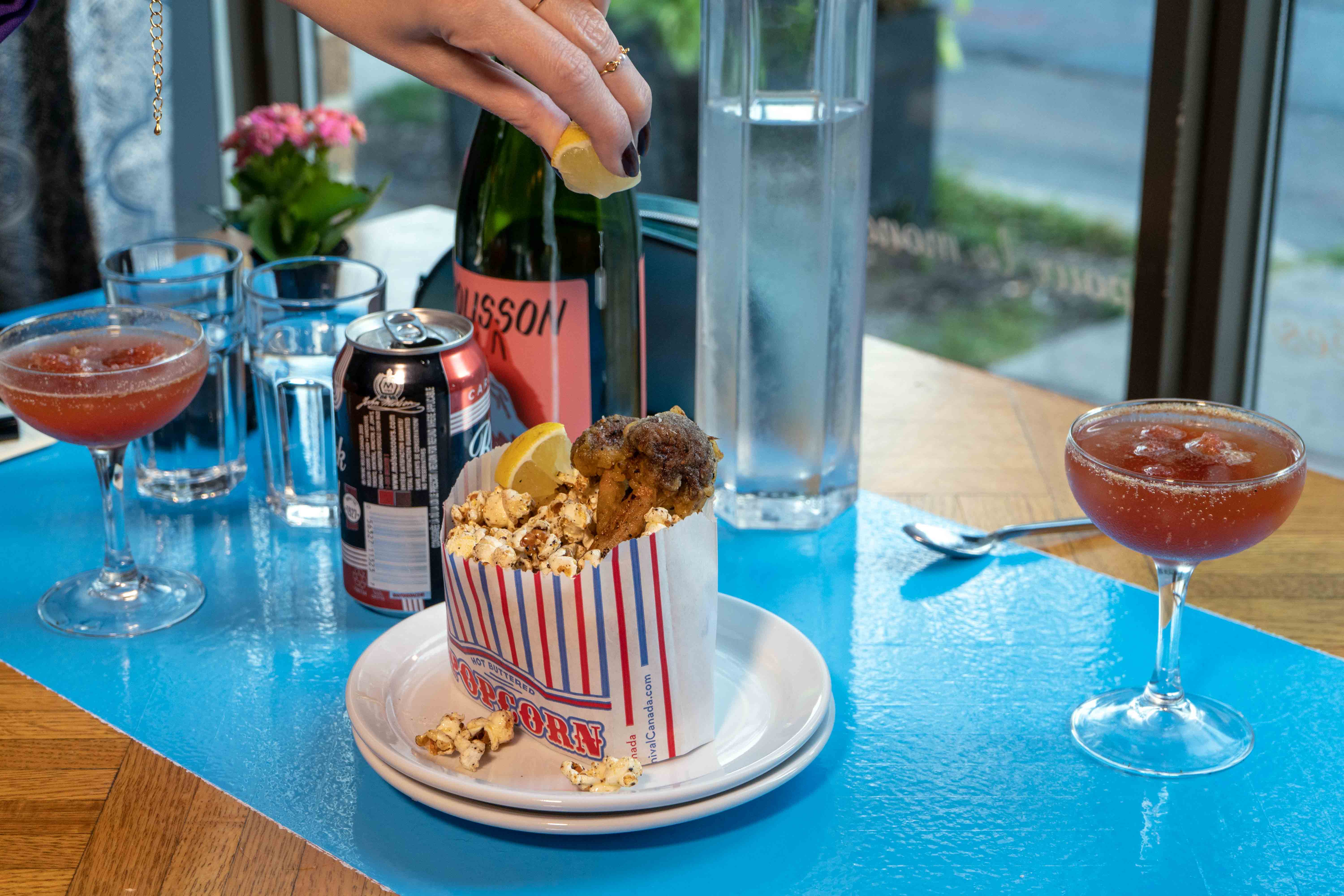 Une main pressant un quartier de citron au-dessus d'un sac rempli de popcorn