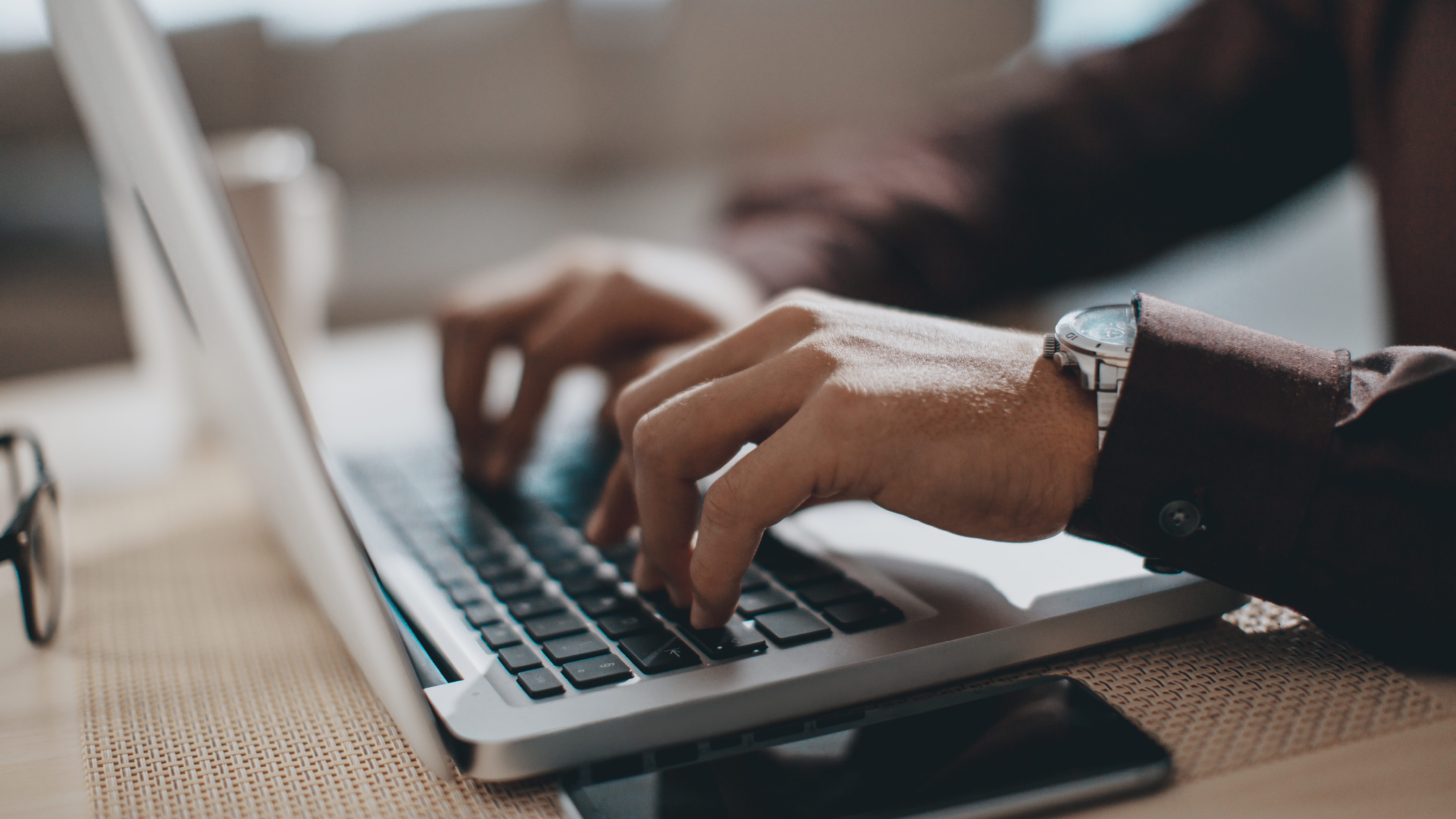 Des mains qui tapent sur un ordinateur portable.