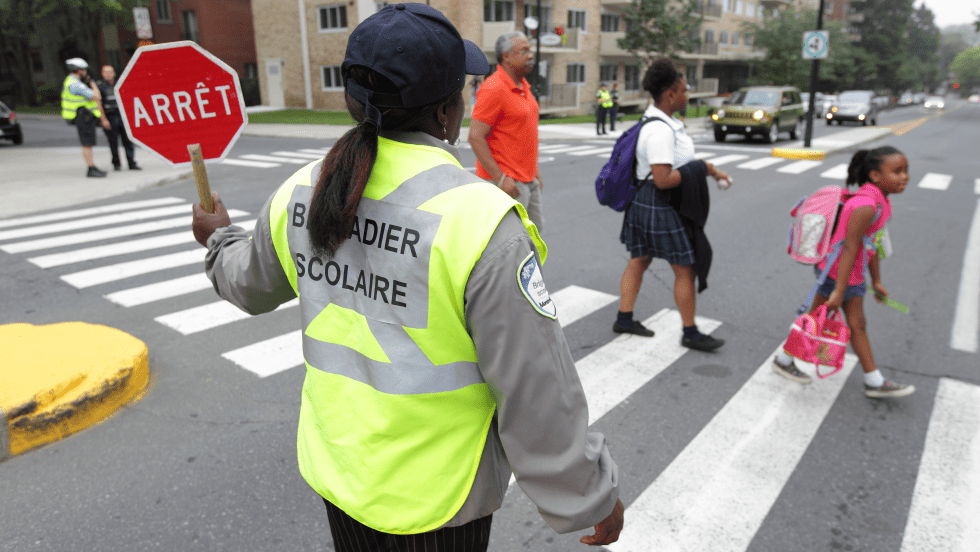 Un brigadier accompagne des enfants à un passage piéton.