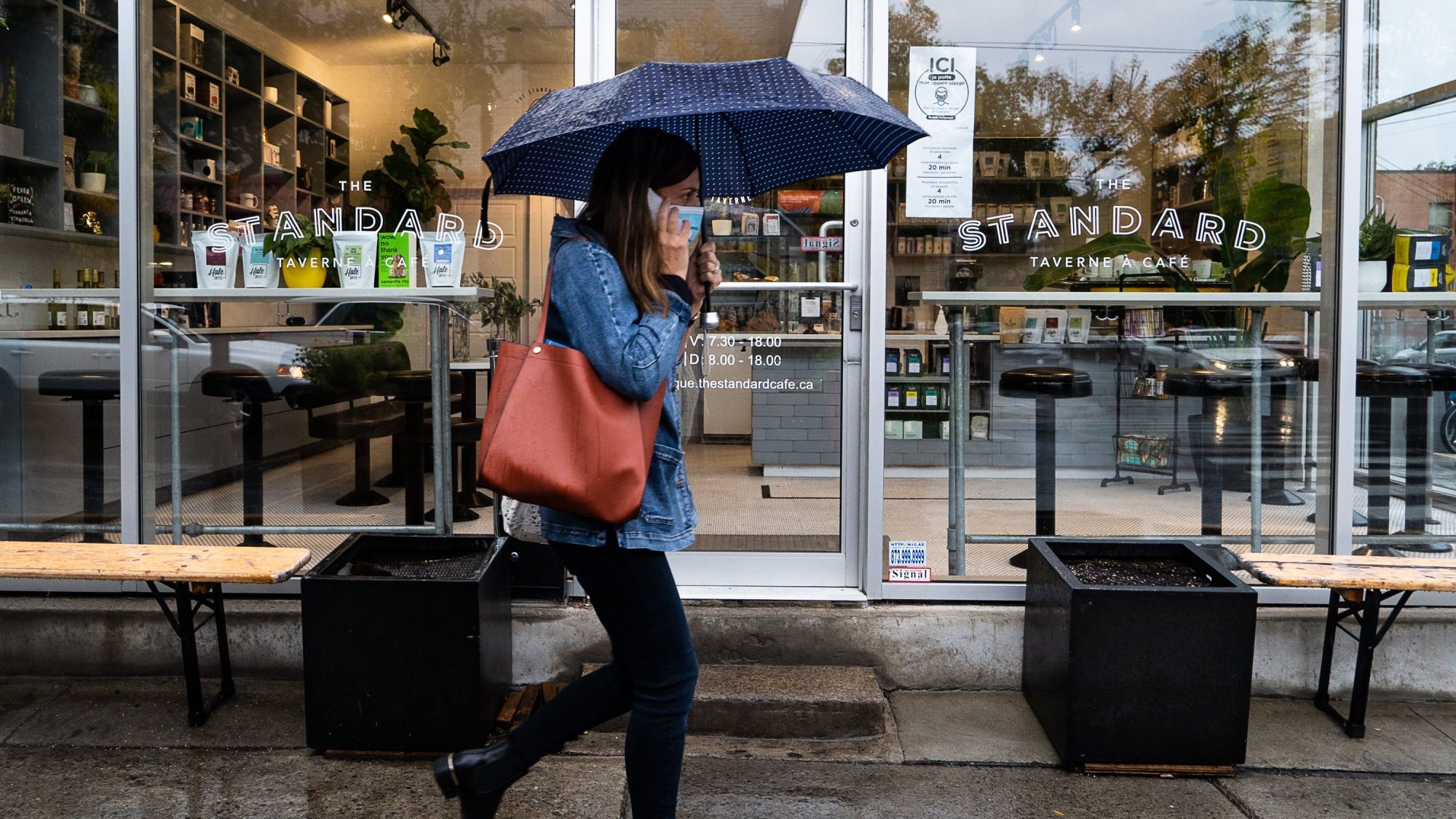 Une dame porte le masque devant un café à Montréal.