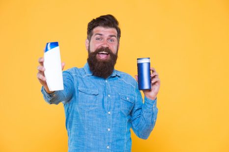 Good choice. Happy hipster hold shampoo and conditioner yellow background. Brutal hipster with hair care products. Bearded hipster with cleansing cosmetics. Grooming routine for hipster