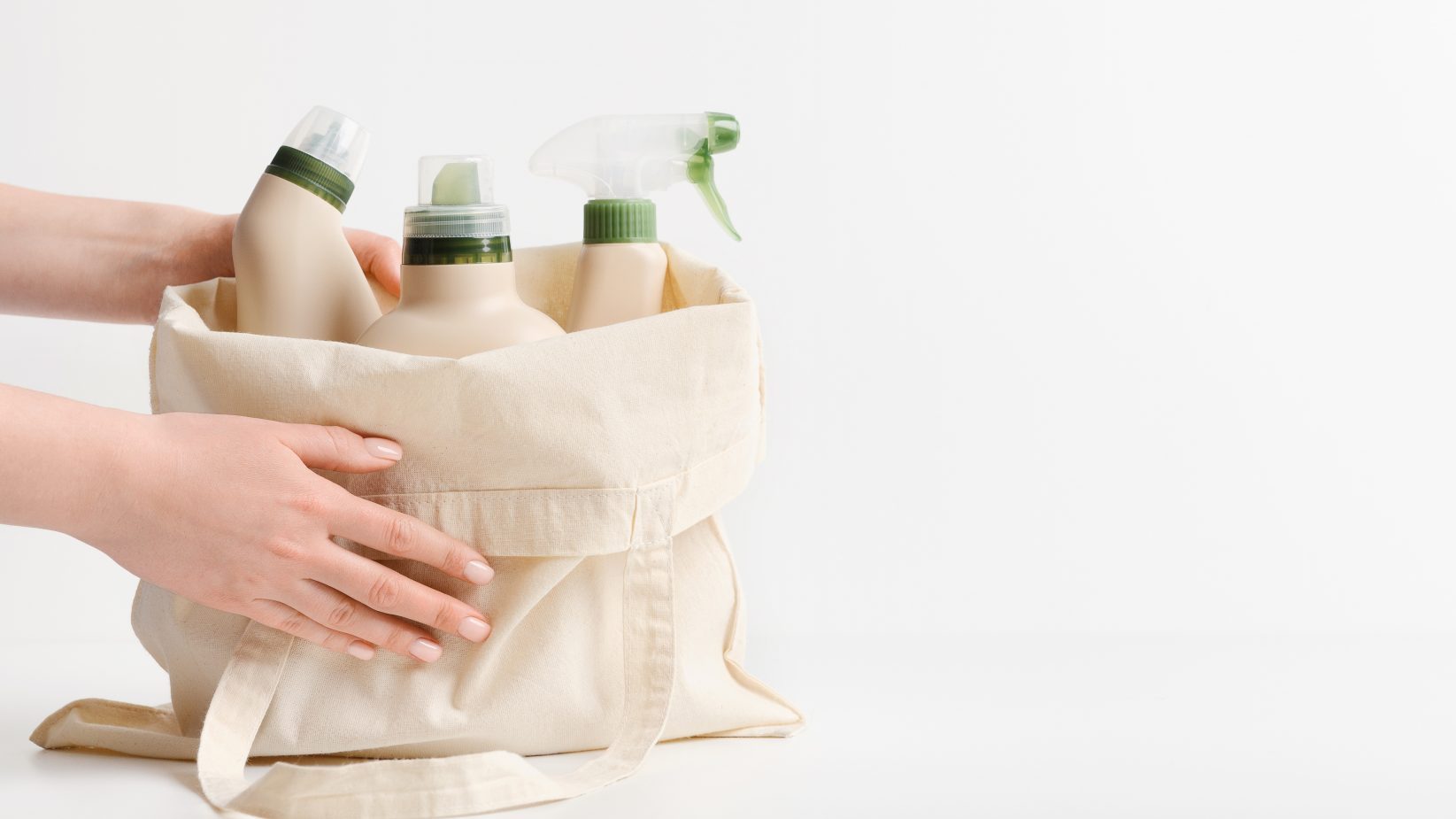 Woman buying many eco friendly home cleaning detergents, reusable bag, white background, panorama, copy space