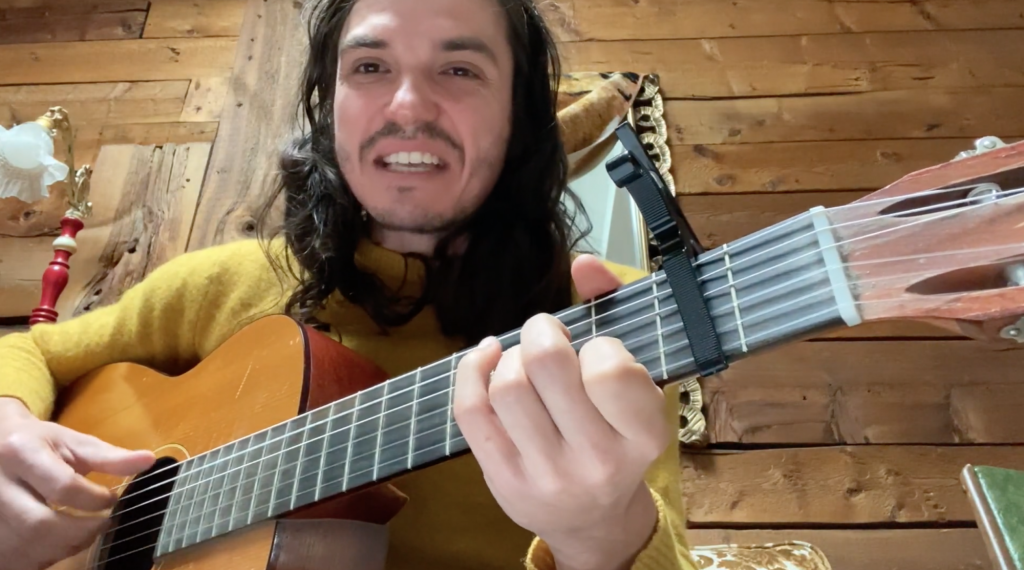 Philemon Cimon avec sa guitare chantant une chanson sur le racisme systémique à la suite de la mort de Joyce Echaquan