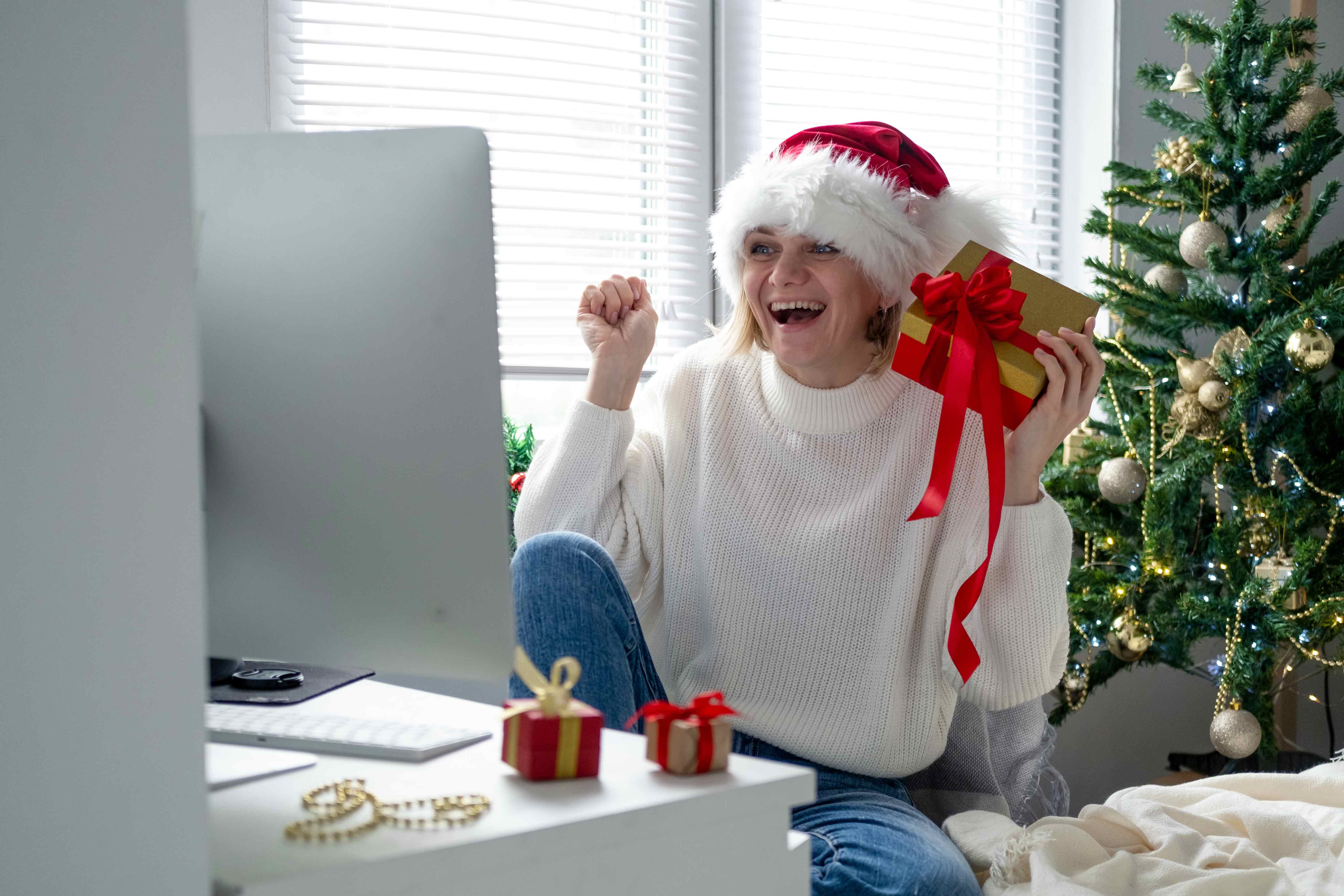 Femme d'âge moyen célébrant les fêtes de Noël devant son ordinateur