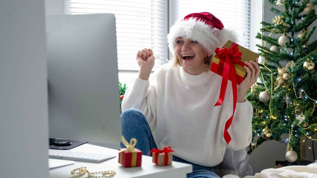 Femme d'âge moyen célébrant les fêtes de Noël devant son ordinateur