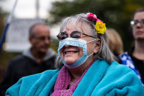 Une femme porte un masque troué lors d'une manifestation anti-masques tenue à Montréal.