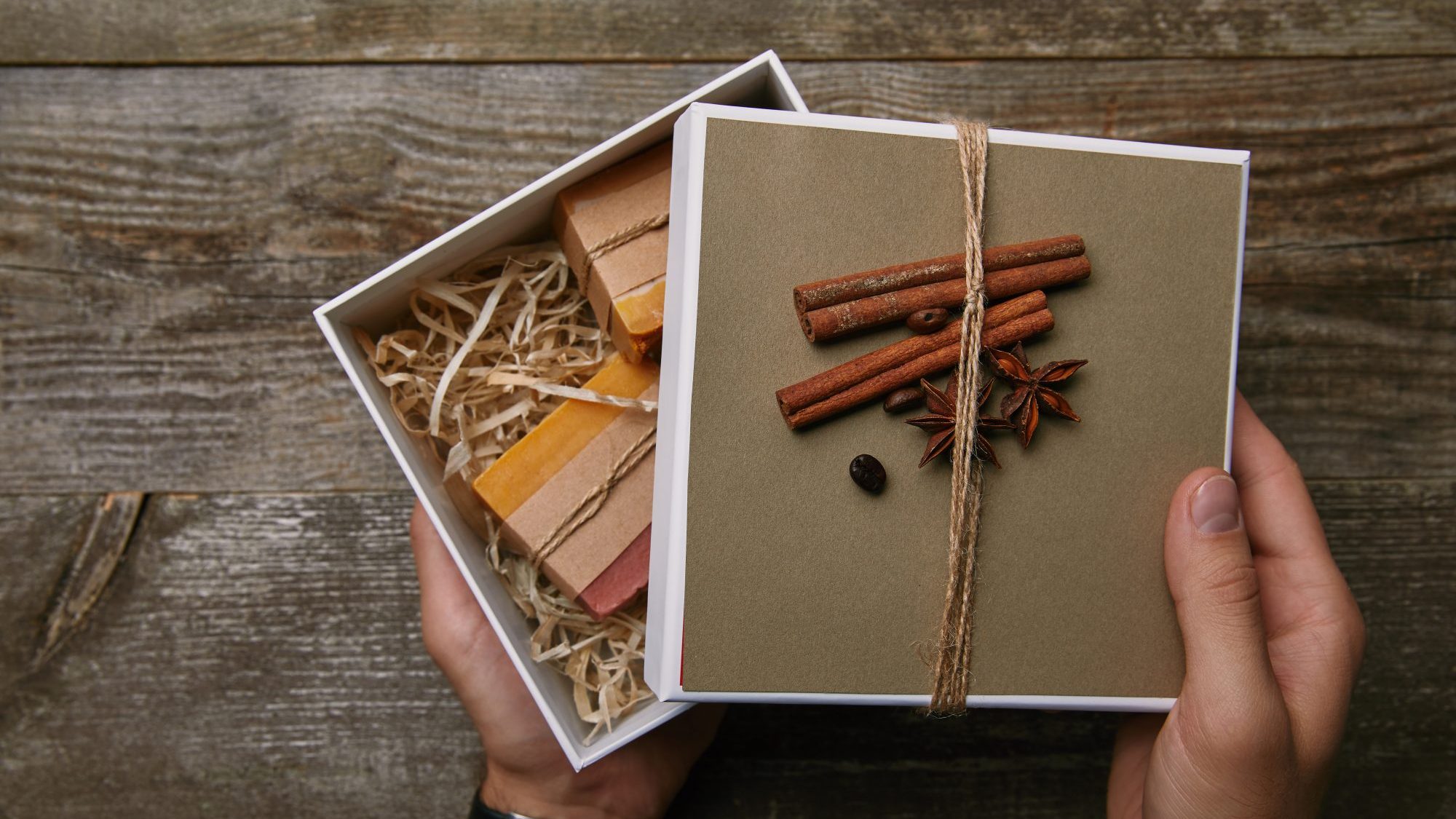 cropped shot of man holding box of handmade soap over wooden table