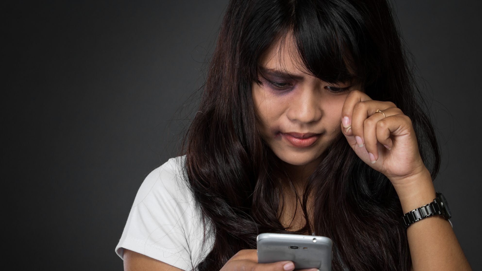 une femme regarde son téléphone et pleure