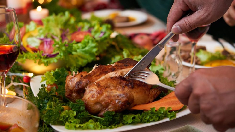 Un homme découpe un morceau de viande durant un souper des Fêtes.