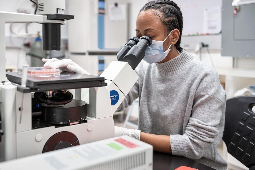 Une femme analyse un échantillon au microscope