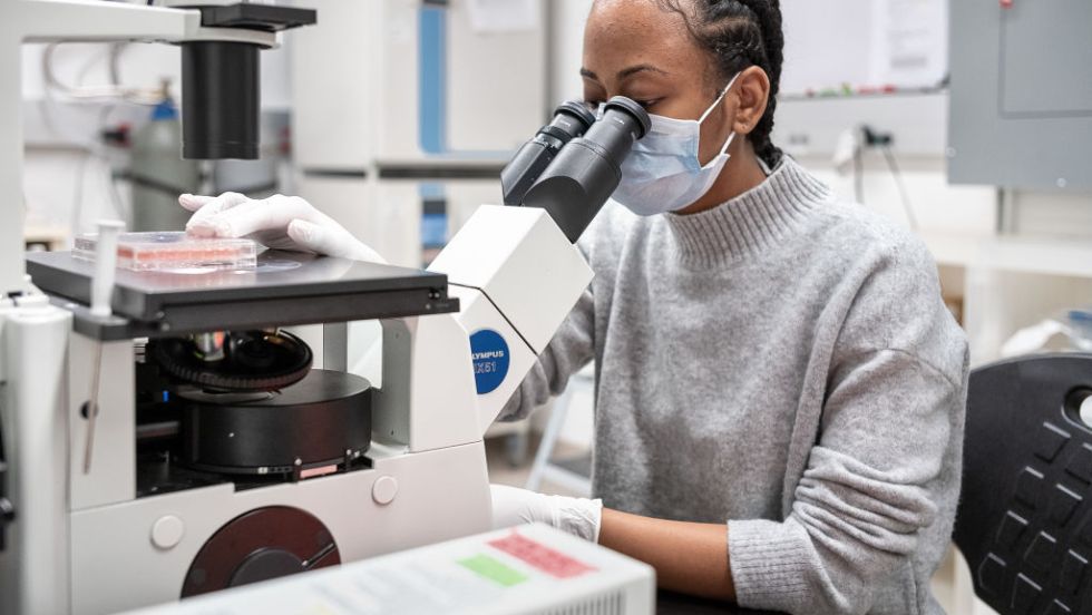 Une femme analyse un échantillon au microscope