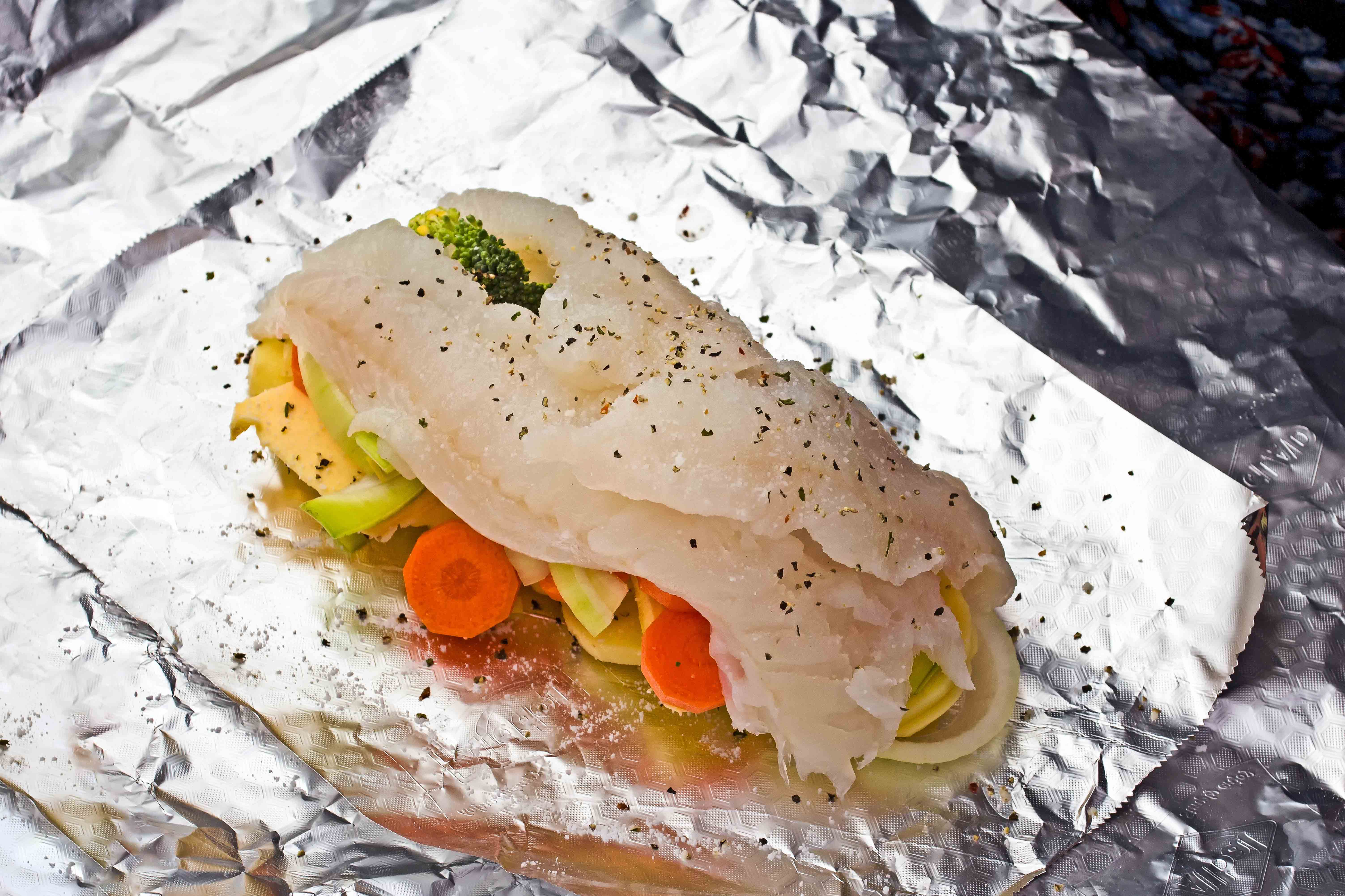 Un filet de poisson couché sur un nid de légumes. Le tout repose sur une feuille de papier d'aluminium.
