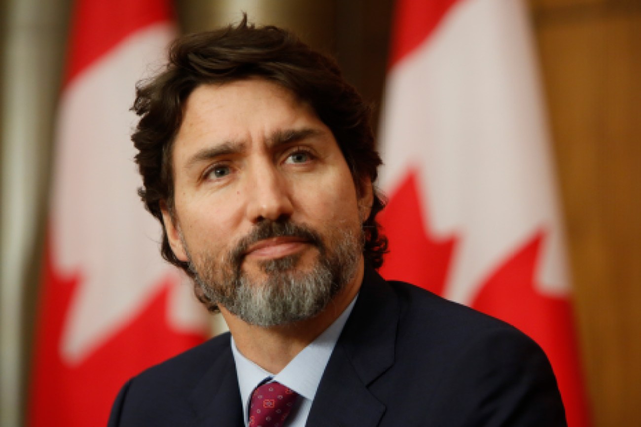Le premier ministre Justin Trudeau devant des drapeaux du Canada lors d'un point de presse sur la COVID-19.
