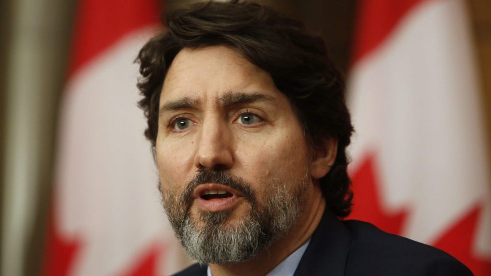 Justin Trudeau, premier ministre du Canada, devant des drapeaux canadiens.