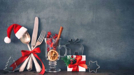 Rustic background for Christmas dinner with cuttlery, gift box and Santas hat