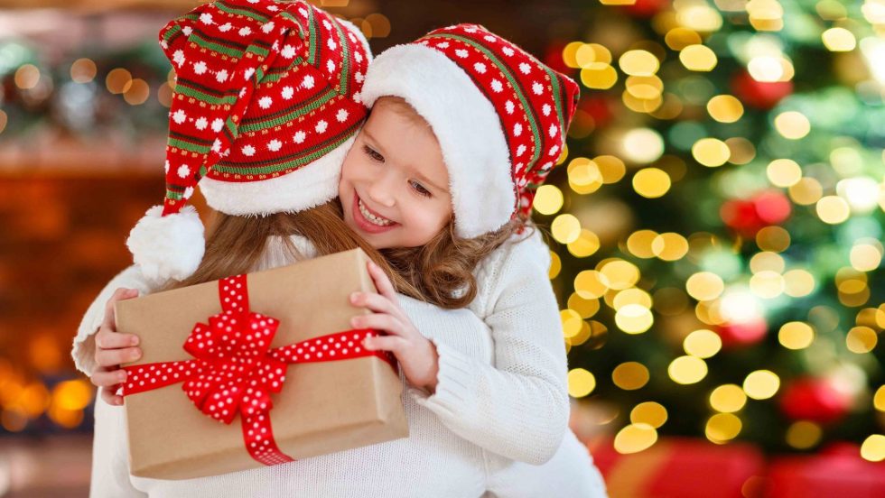 Heureuse famille mère et fille donnant un cadeau de Noël et s'embrassant