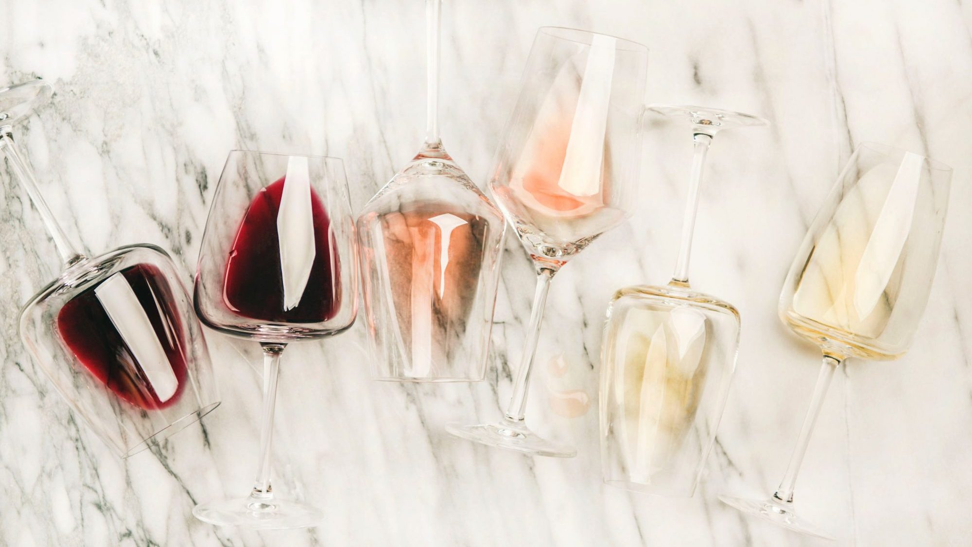 Coupes de vin rouge, blanc et rosé sur fond de marbre.