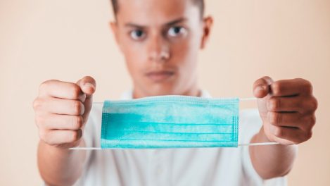 Jeune homme montrant un masque pour se protéger de la COVID-19