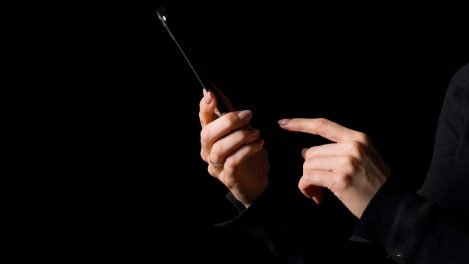 Des mains avec un téléphone cellulaire dans le noir.