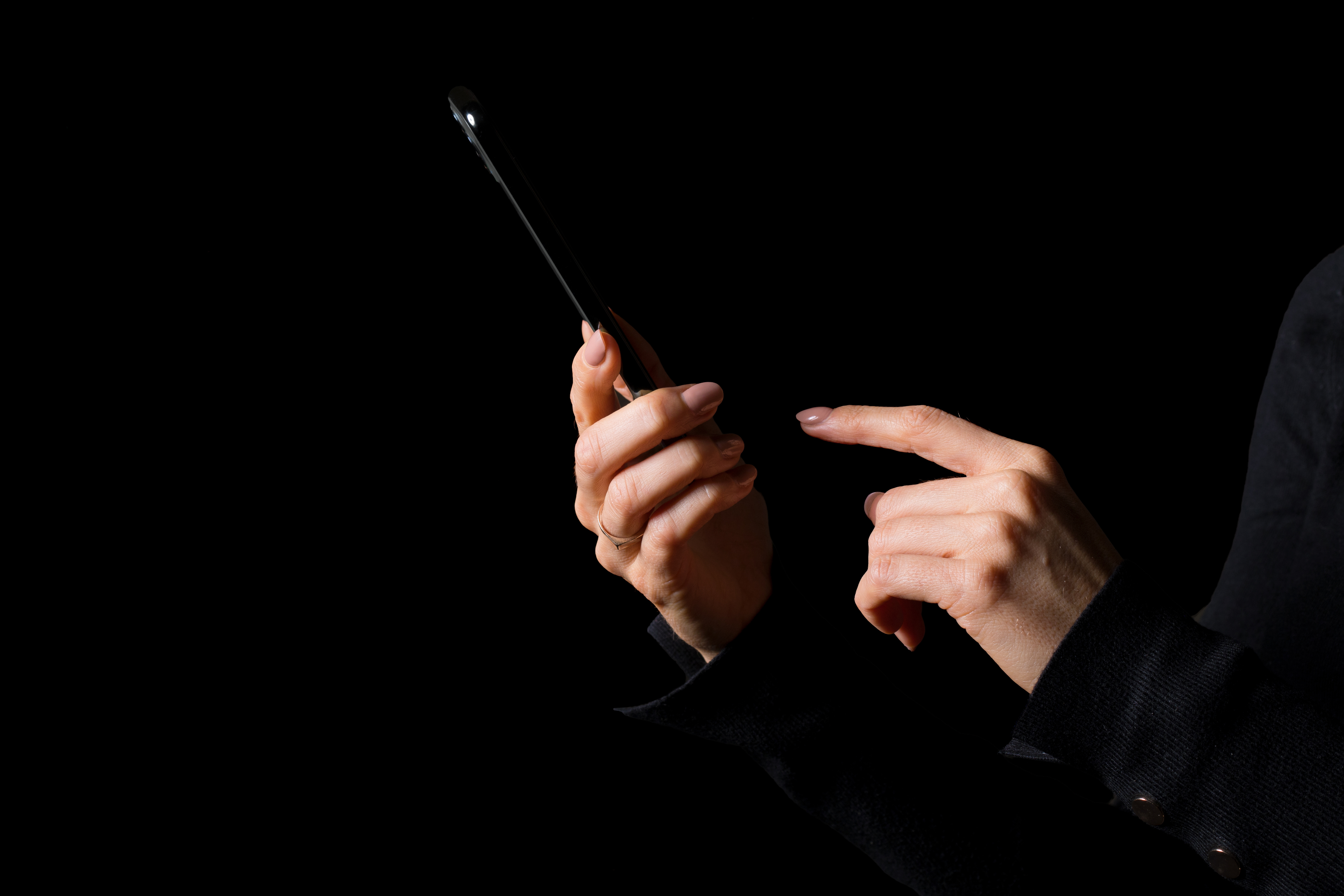 Des mains avec un téléphone cellulaire dans le noir.