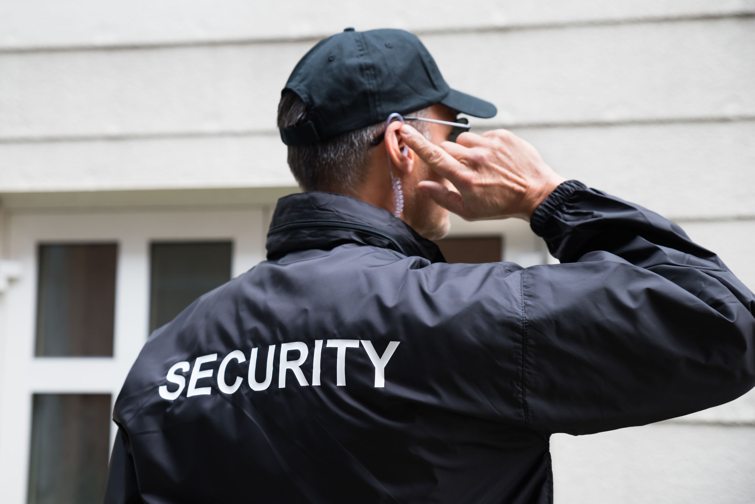 Un agent de sécurité à l'écoute devant une maison, vu de dos. L'Accueil Bonneau a remplacé 11 intervenants en itinérance par des agents de la firme Garda.