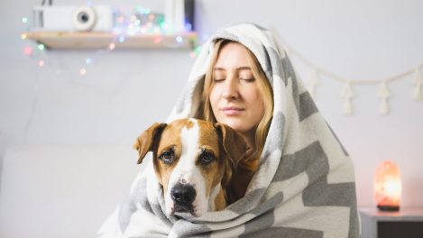 Jeune femme et son chien tout deux emmitouflés dans une couverture