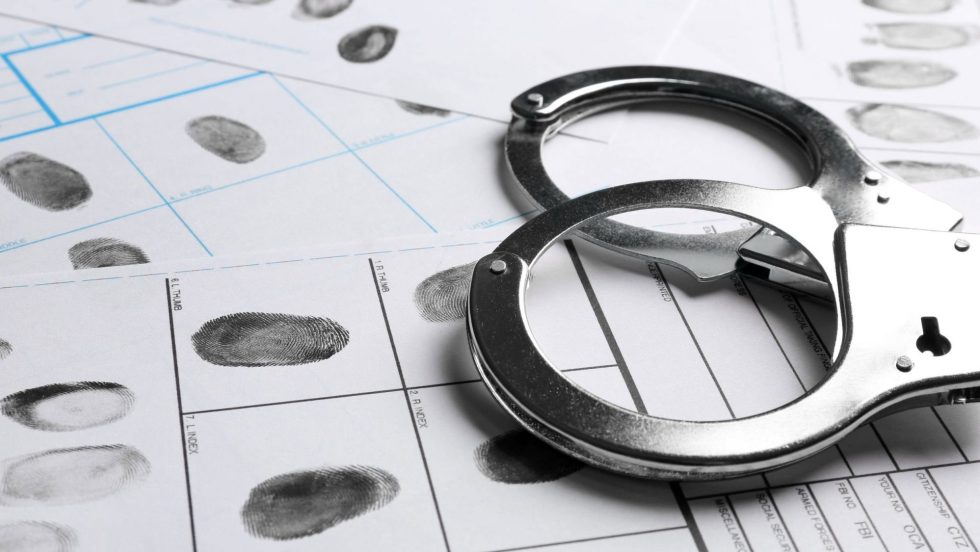 des menottes et des empreintes digitales symbolisant une personne avec un casier judiciaire.