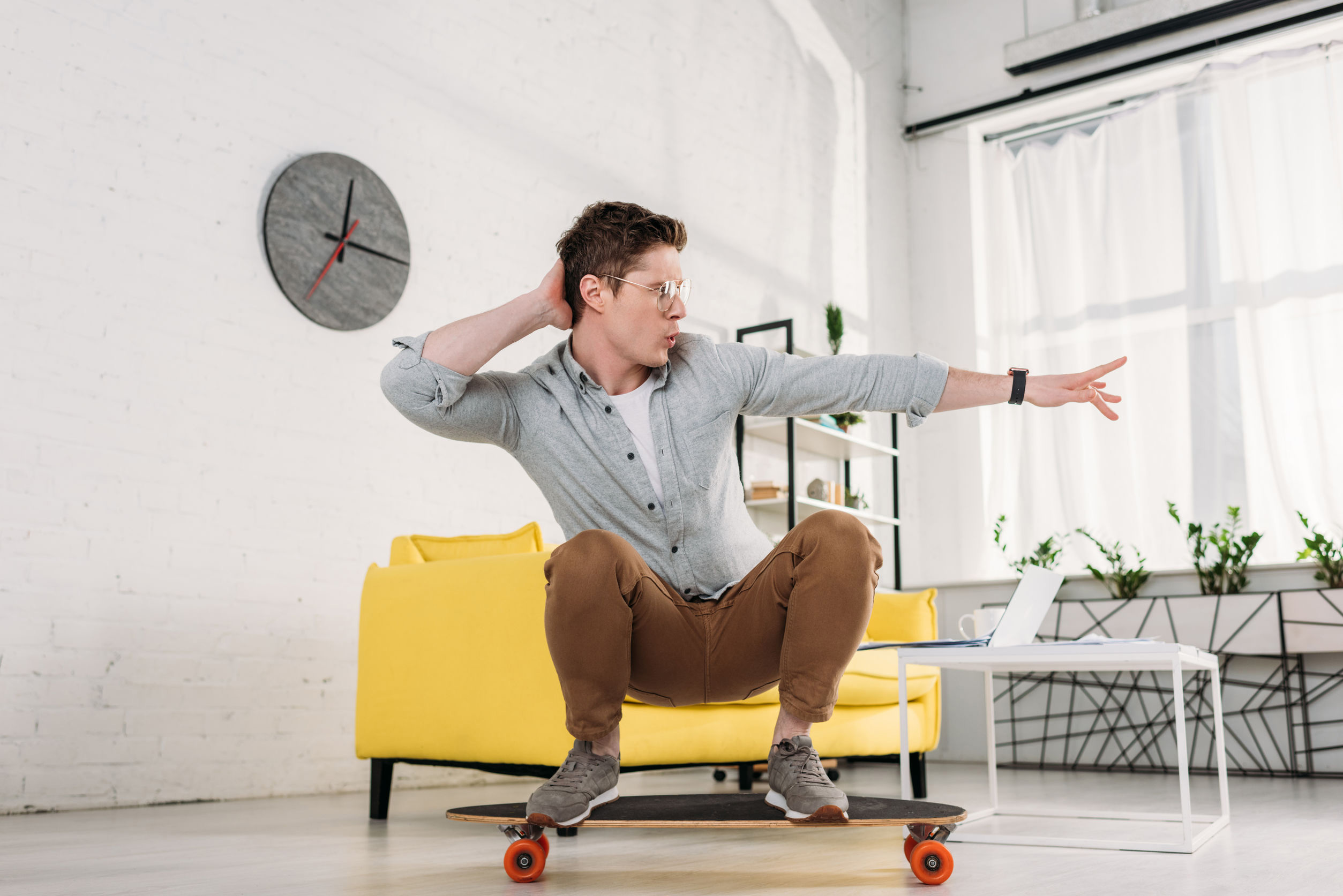funny man in glasses riding skateboard at home