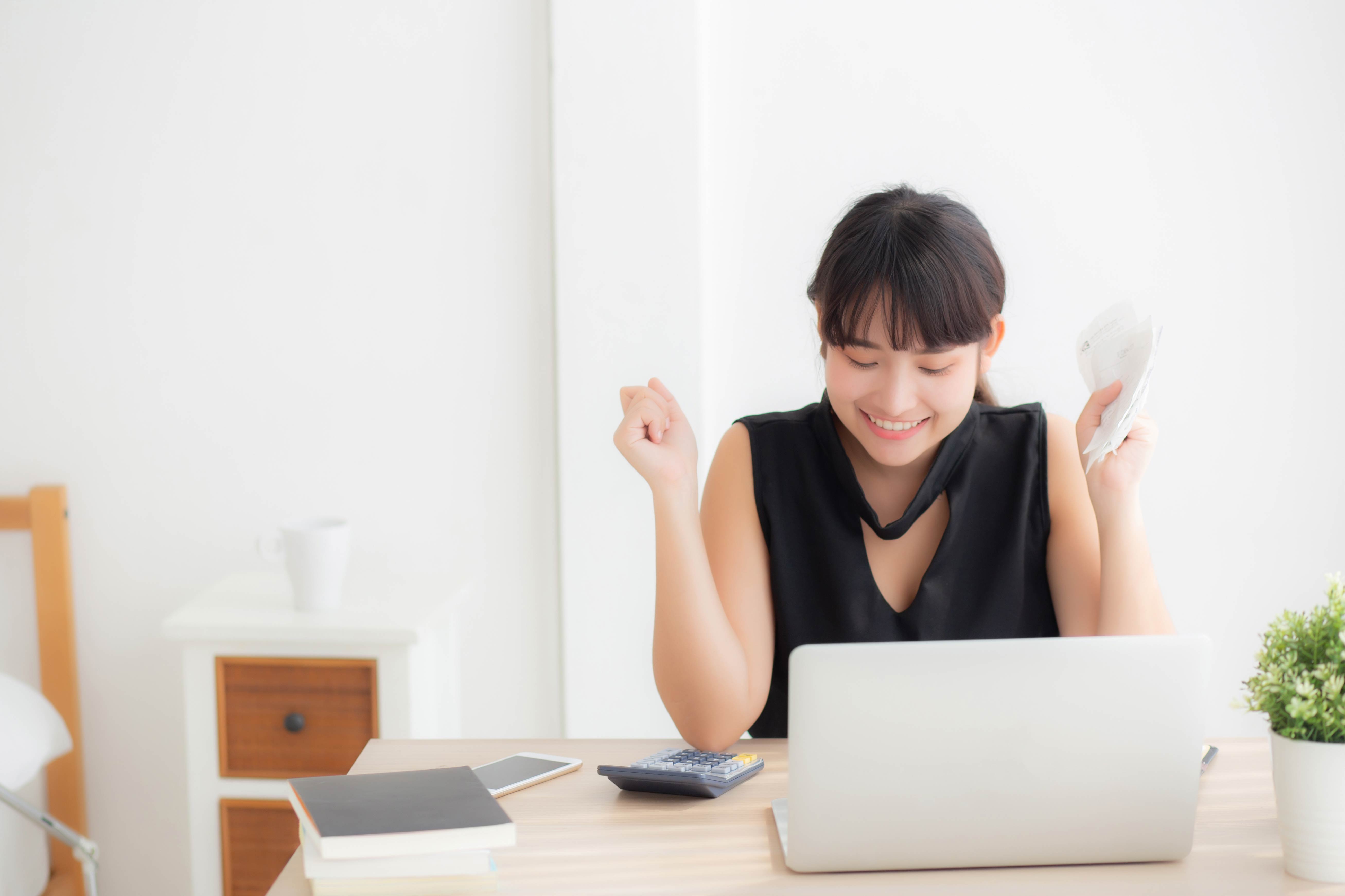 Beautiful young asian woman calculating finance household and writing notebook on desk, girl checking bill and success for saving expenses household with target, debt closure, business concept.