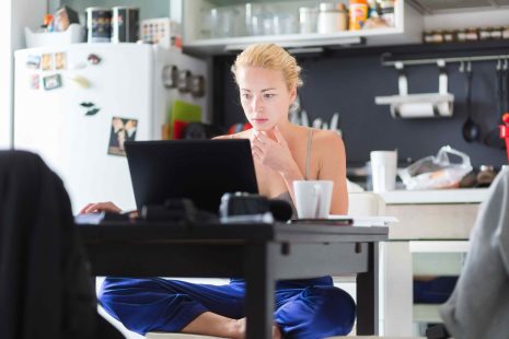 Pigiste Femme dans ses vêtements d'accueil occasionnel de travail remotly de sa table à manger le matin. Accueil cuisine dans l'arrière-plan.