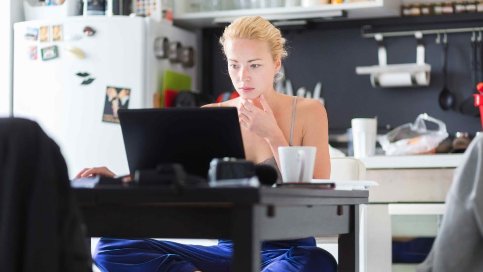 Pigiste Femme dans ses vêtements d'accueil occasionnel de travail remotly de sa table à manger le matin. Accueil cuisine dans l'arrière-plan.
