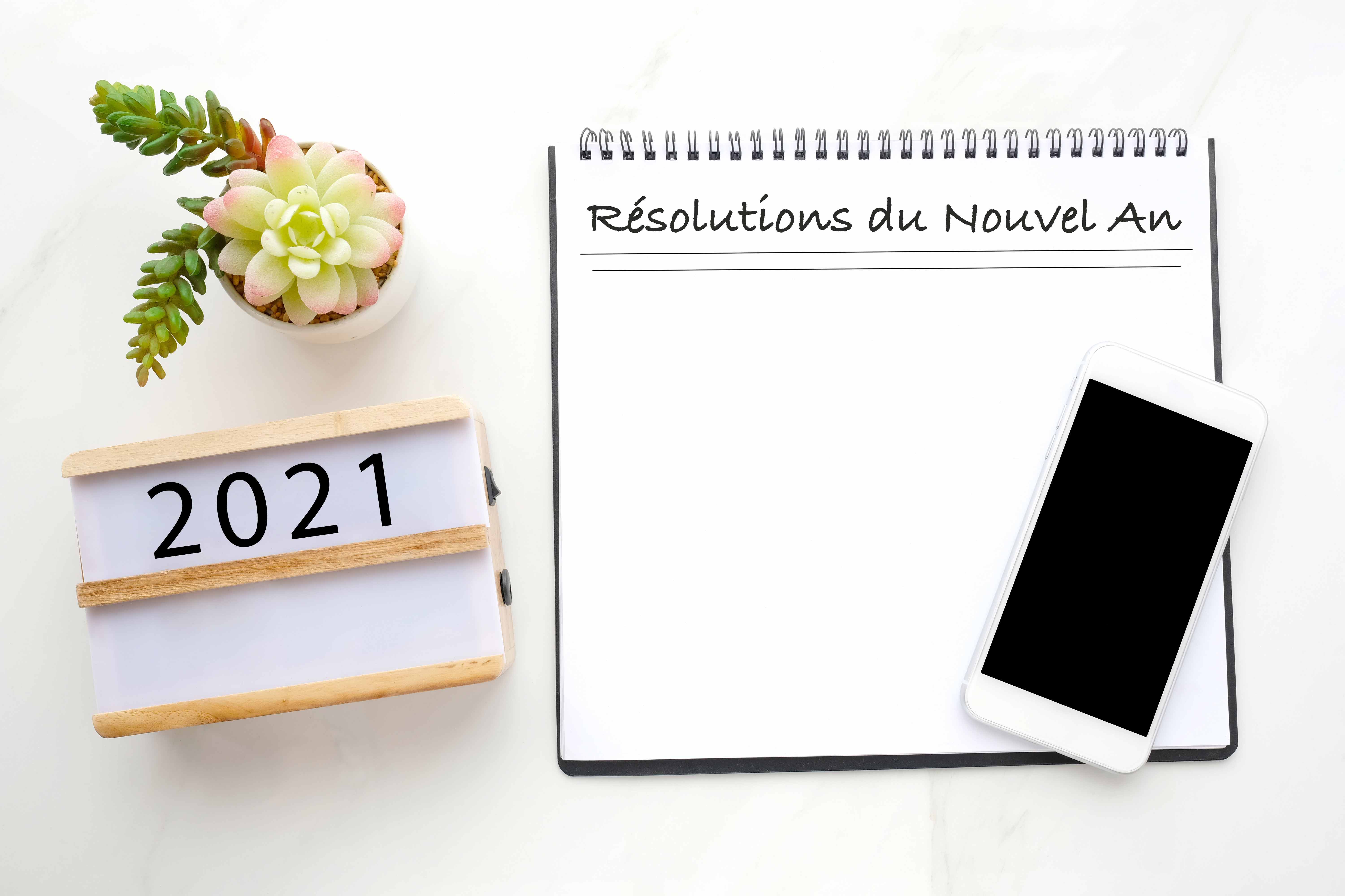 2021 resolution on blank notebook paper, smart phone with blank screen on white marble background, 2019 new year mock up, template, flat lay