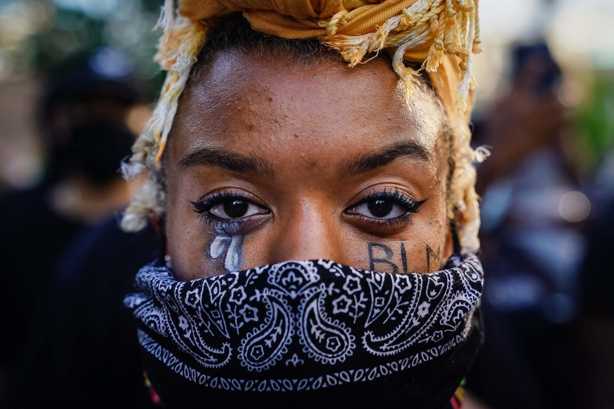 Gros plan du visage d'une femme portant un masque, avec du maquillage de larmes sous ses yeux, en marge de la Journée internationale des femmes.