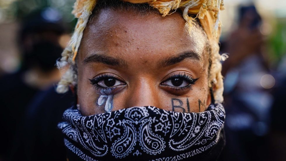 Gros plan du visage d'une femme portant un masque, avec du maquillage de larmes sous ses yeux, en marge de la Journée internationale des femmes.