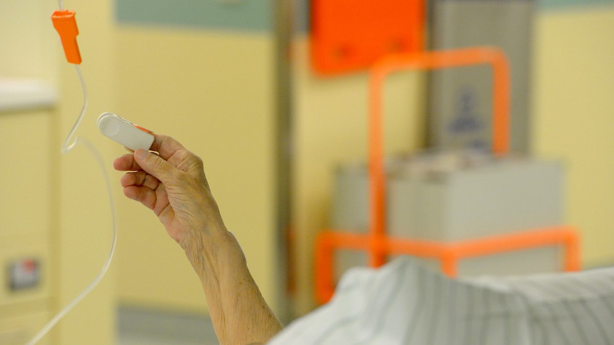 Une personne âgée hospitalisée pour la COVID-19 lève un bras.