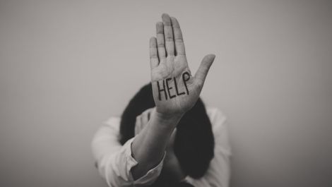 Une femme tient une main ouverte avec le mot «help» écrit dessus en protestation contre la violence conjugale et les féminicides
