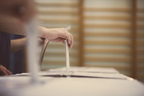 une personne dépose un bulletin de vote dans un urne