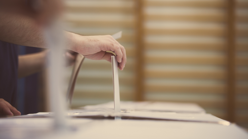 une personne dépose un bulletin de vote dans un urne
