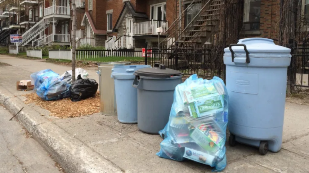 Des sacs et bacs de déchets et de matières résiduelles le long d’un trottoir.