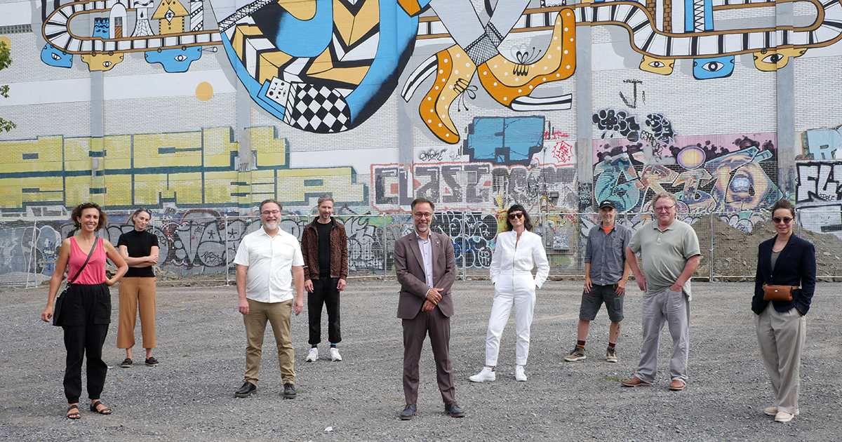 Les représentants de l'arrondissement du Plateau-Mont-Royal, dont le maire Luc Rabouin (au centre), et des membres de la communauté artistique se tiennent devant une murale située sur la rue de Gaspé