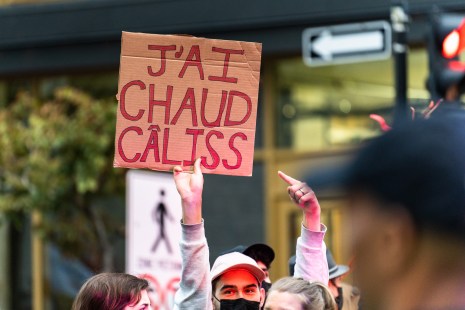 Un manifestant écologiste tient une pancarte qui dit «J'ai chaud câliss» pendant une manifestation pour l'environnement avant le débat des chefs à TVA.