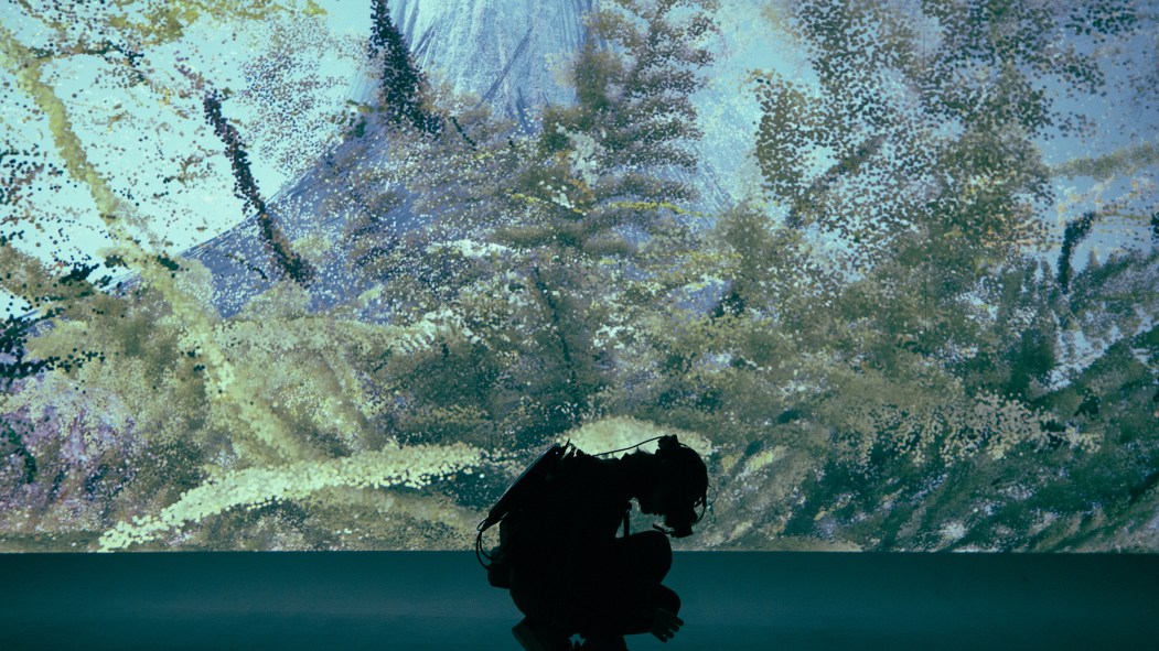 Un homme en scaphandrier est accroupit devant un énorme aquarium dans l'exposition «We Live in an Ocean of Air» de Marshmallow Laser Feast.