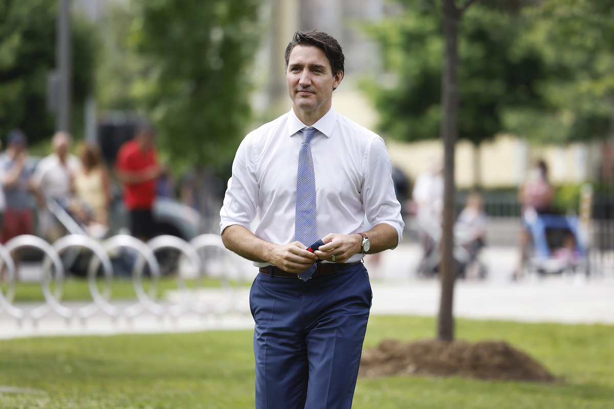 Le premier ministre Justin Trudeau en chemise et cravate, se promenant dans un parc l'été peu avant les élections fédérales 2021.