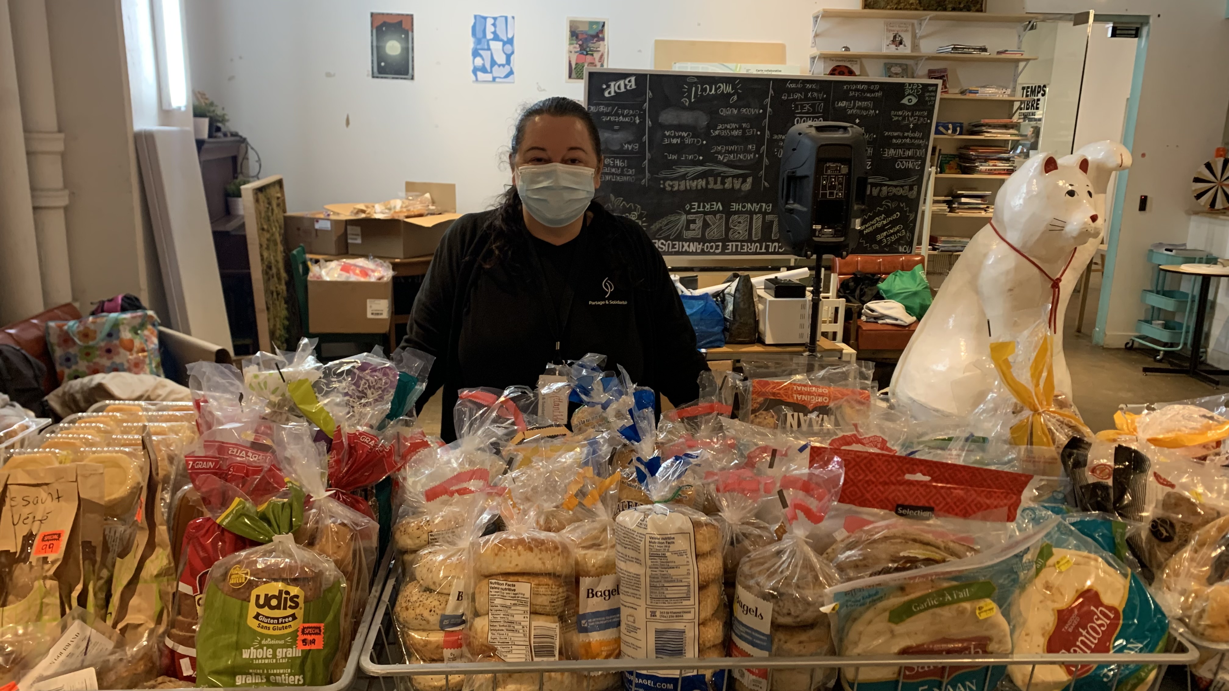 Atlantide Desrochers devant l'étalage de pains et viennoiseries prêts à être distribués