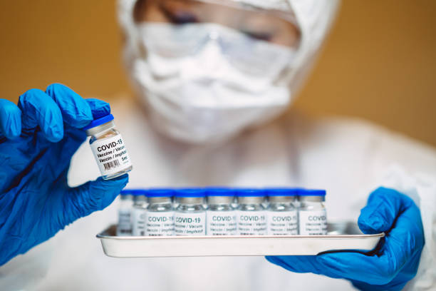 Une travailleuse de la santé masquée manipule des fioles de vaccin contre la COVID-19.