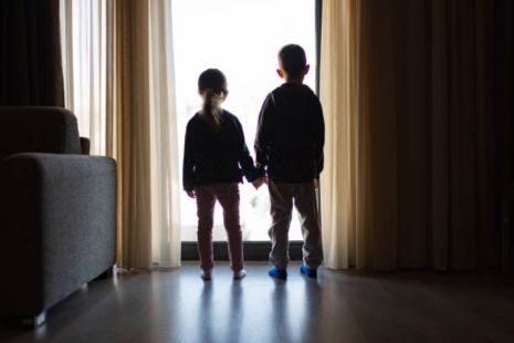 Les silhouettes de deux enfants se tiennent debout devant le portique d'un logement.