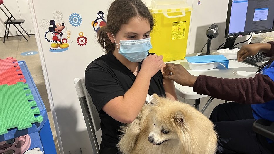 Eva se fait vacciner avec la chienne Dalia sur les genoux.