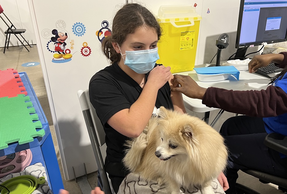 Eva se fait vacciner avec la chienne Dalia sur les genoux.